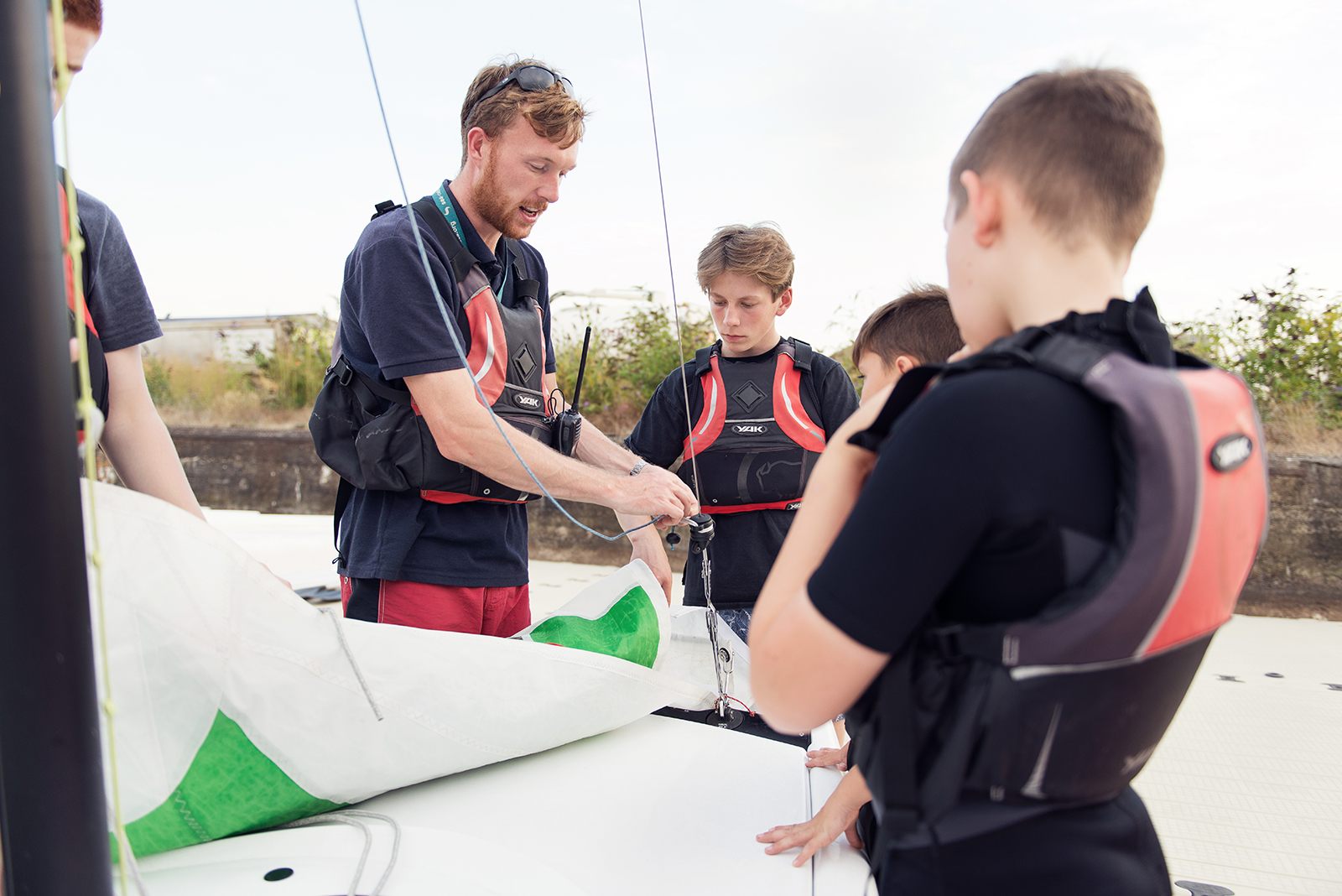 Instructor showing cadets how to attach a sail to a boat